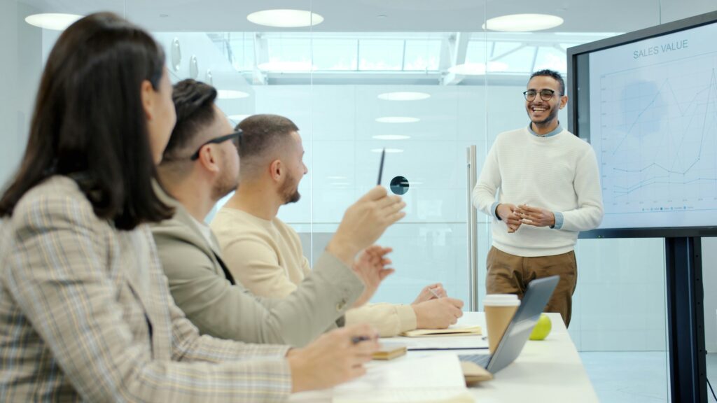 four people in a meeting room one standing infront of a screen having a meetila