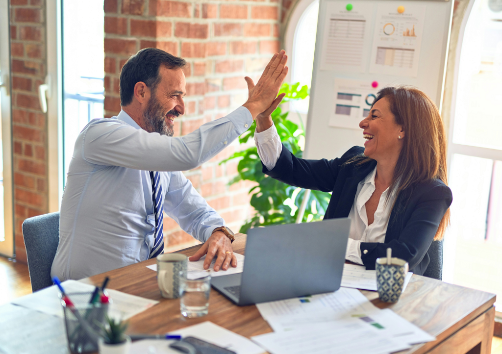 Couple at a desk with laptop celebrating forming a company