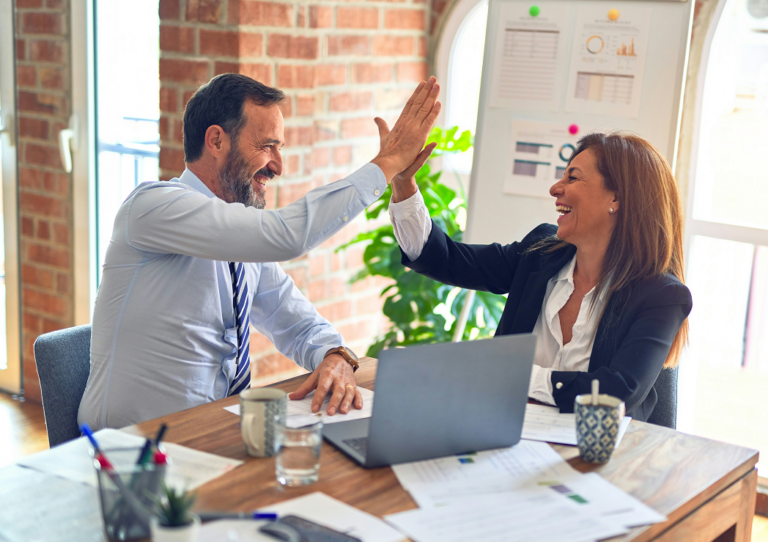 Couple at a desk with laptop celebrating forming a company
